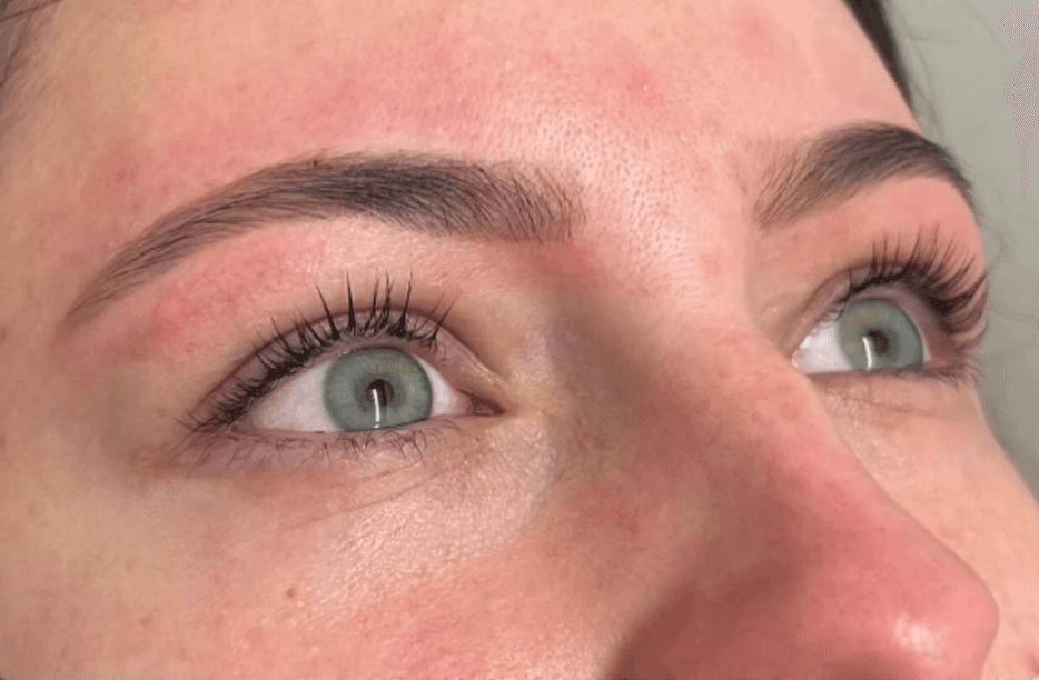 Close-up of a person's eyes with long eyelashes and well-groomed eyebrows, looking upward.